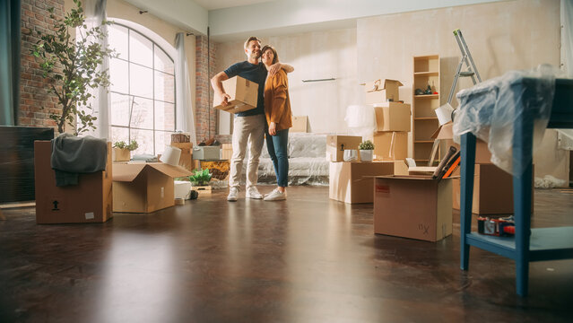 Couple standing in new apartment with moving boxes