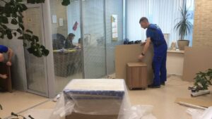 Movers disassembling office furniture during a corporate relocation