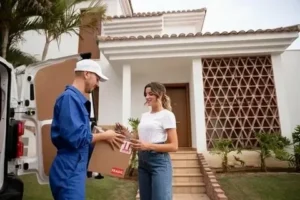 Delivery man handing a package to a woman at the entrance of a modern home