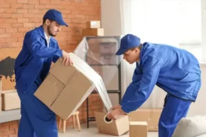 Professional movers wrapping furniture and boxes during home relocation